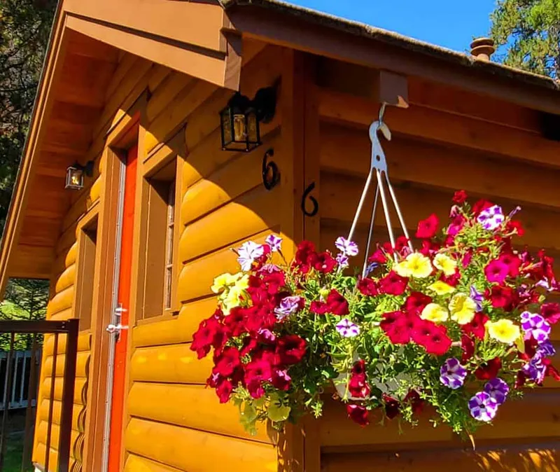 Becker's Chalets log cabin entrance with red and yellow flowers blooming.