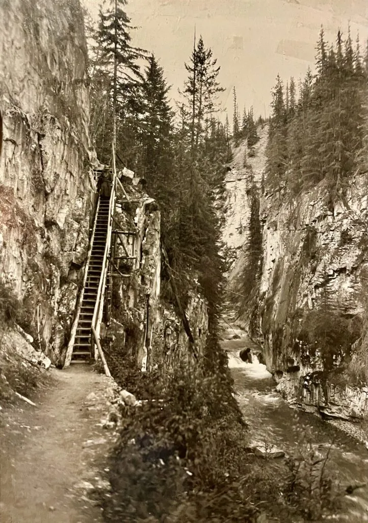 Wooden stairs climb a limestone canyon wall beside a creek at Johnston Canyon Lodge.