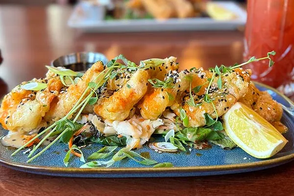 Kilmorey Lodge patio dining plate of seared shrimp with fresh greens and lime.