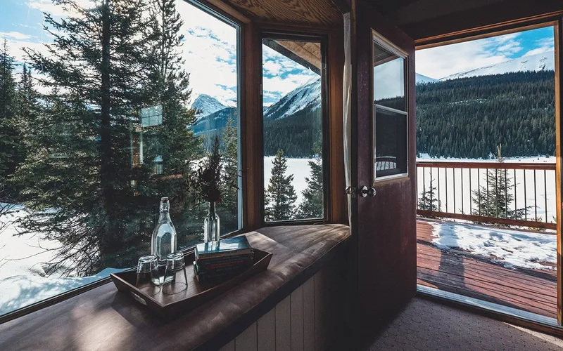 Mount Engadine Lodge cabin interior with large windows framing snowy lake and alpine forest views.