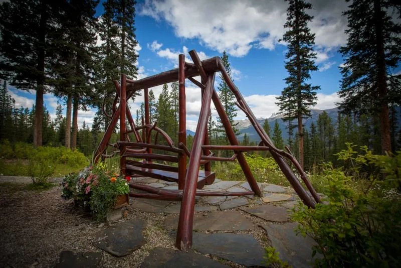 Wooden ranch gate entrance with flower planter at Paradise Lodge, surrounded by evergreen forest and mountains.