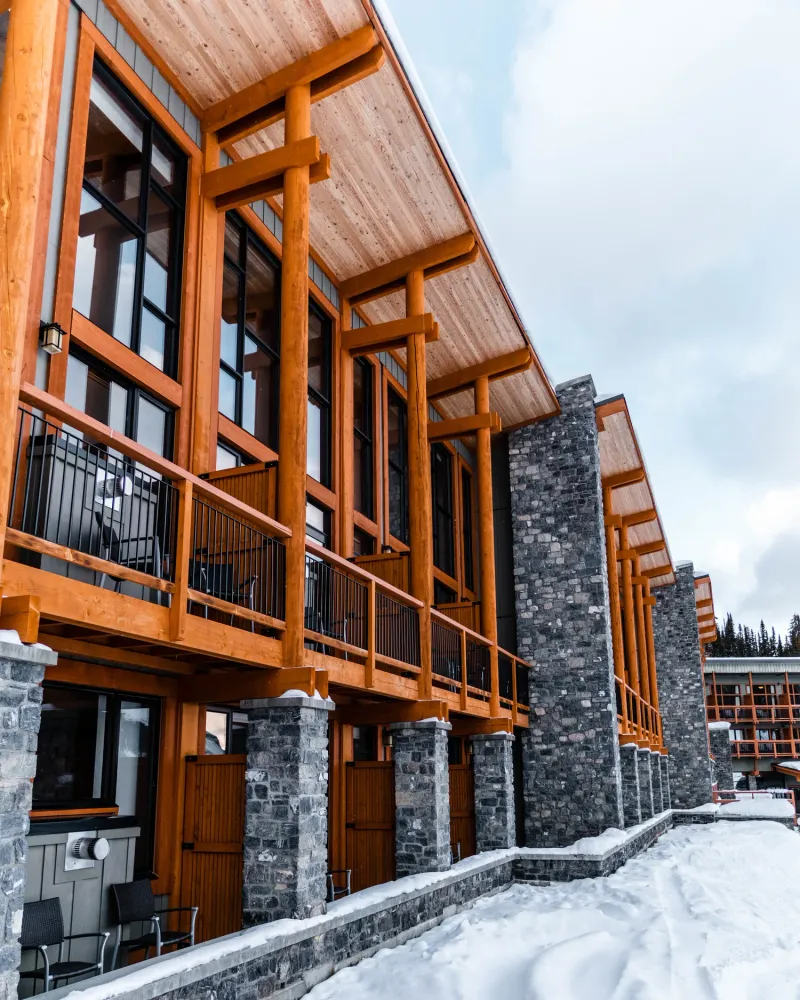 Sunshine Mountain Lodge timber-frame and stone exterior with expansive windows in snow.